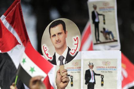 A student holds a sign with a picture of Syria's President Bashar al-Assad during a protest by a students' national union against possible U.S. military action in Syria, in Brasilia September 6, 2013. REUTERS/Ueslei Marcelino