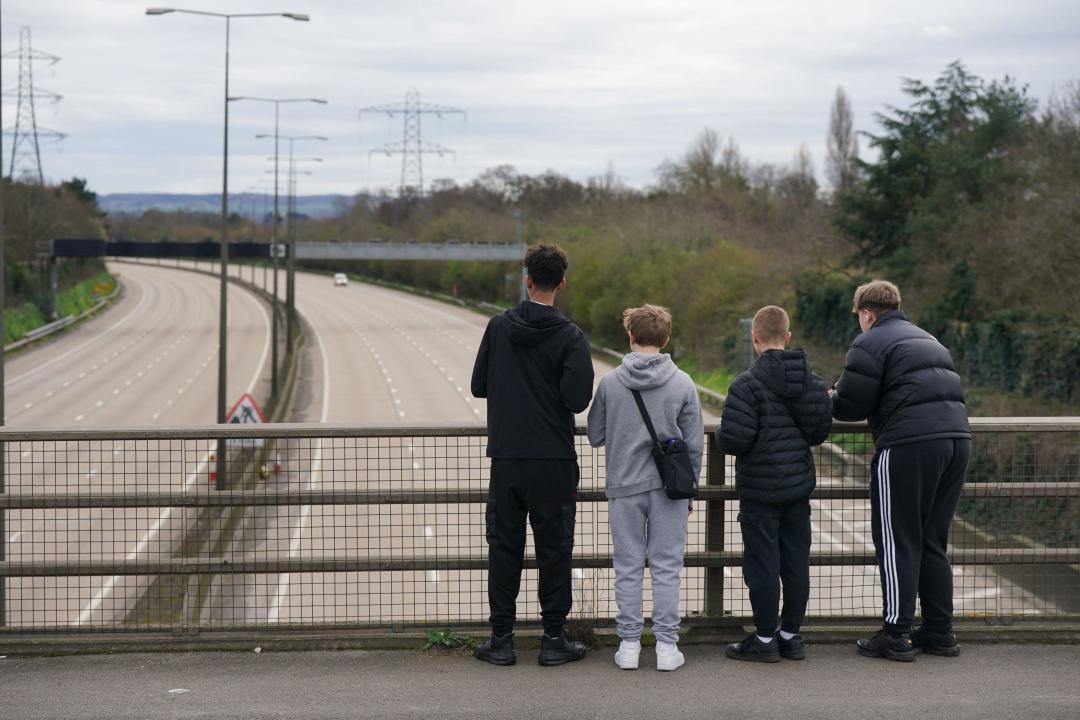 Young boys stand on the Parvis Road bridge in Byfleet, that crosses over a closed section of the M25 between Junctions 10 and 11, while a bridge is demolished and a new gantry is installed. Picture date: Saturday March 16, 2024.