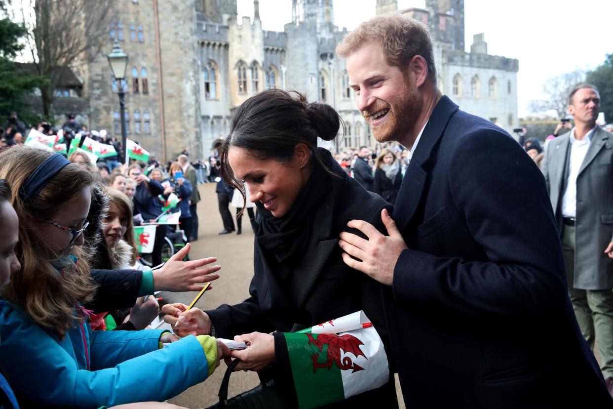 Prince Harry and Meghan Markle sign autographs and shake hands with children as they arrive to a walkabout at Cardiff Castle on January 18, 2018 in Cardiff, Wales (Getty)