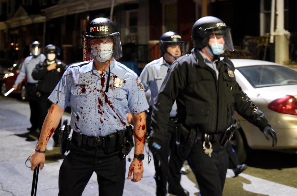 A police officer is pictured on Tuesday night splattered with a red substanceAP