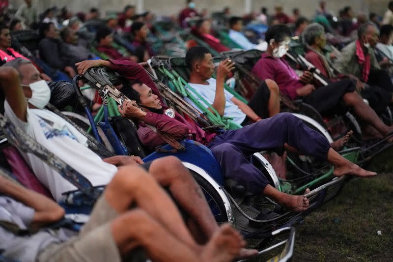 Tricycle drivers attend an outdoor movie screening held by a private organization in Phnom Penh