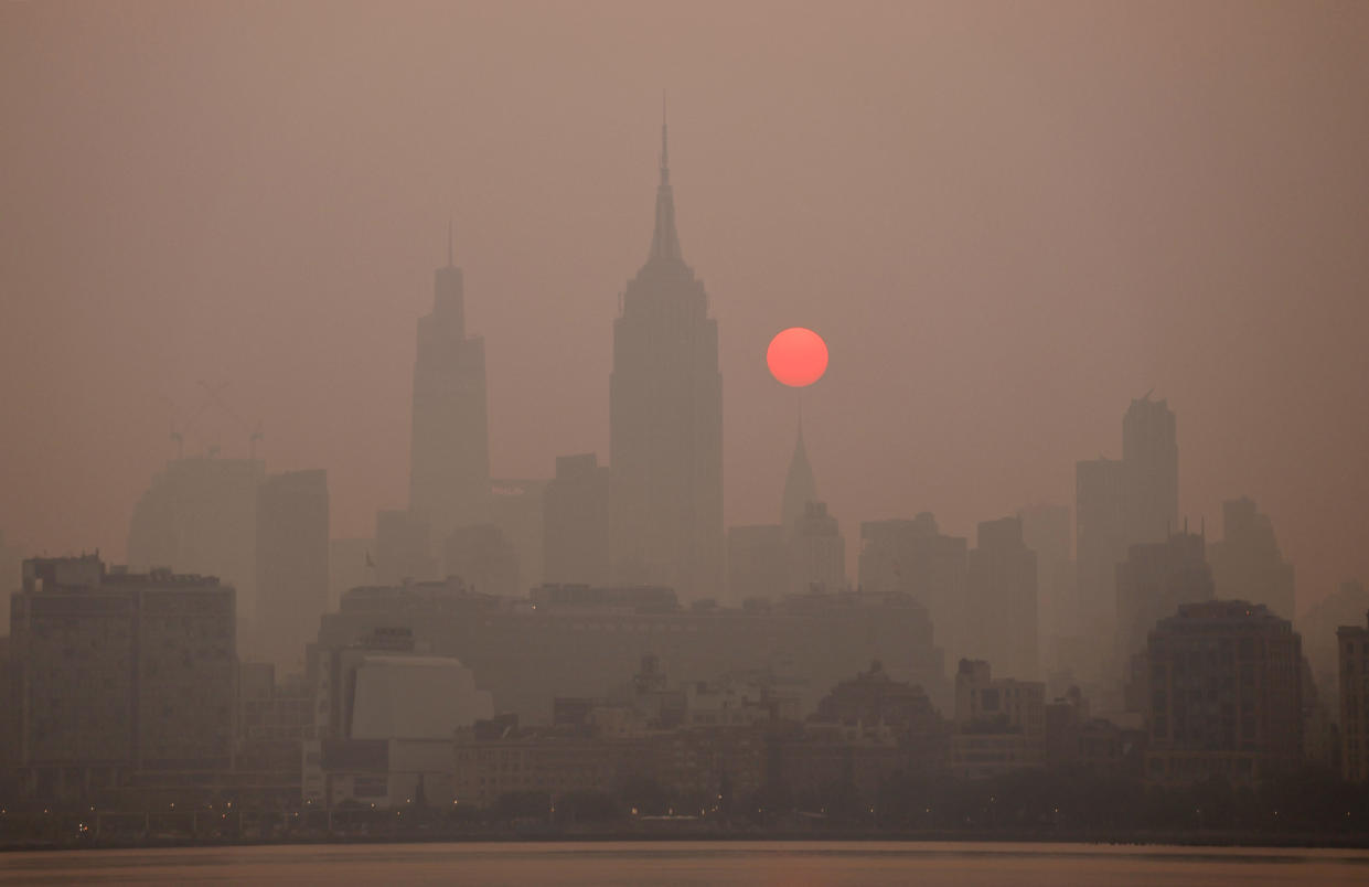 A red sun rises in a dark smoky sky.