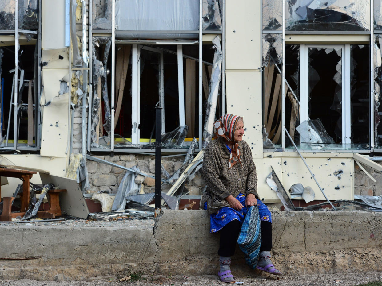 An elderly woman sits outside a damaged building in Pervomaisk, which is held by rebels loyal to the Lugansk People's Republic: Getty