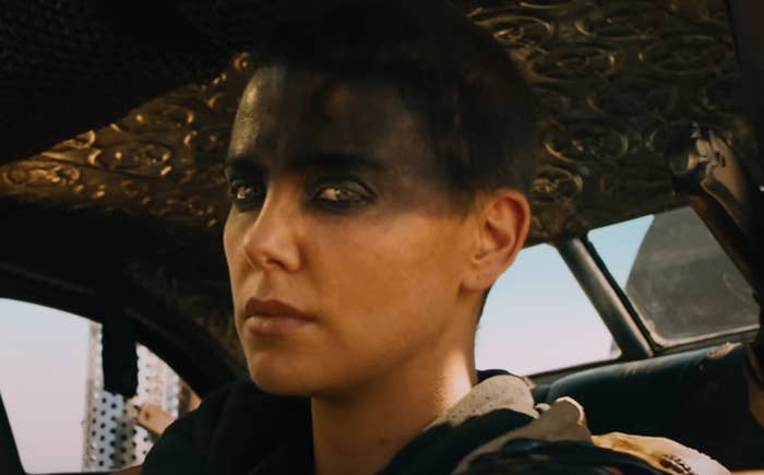 Charlize as Furiosa is shown with a determined look as she sits in a vehicle
