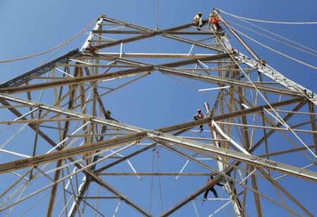 FILE PHOTO: Workers install new power lines on an electric pole on the outskirts of Ajmer, India, February 20, 2017. REUTERS/Himanshu Sharma/Files