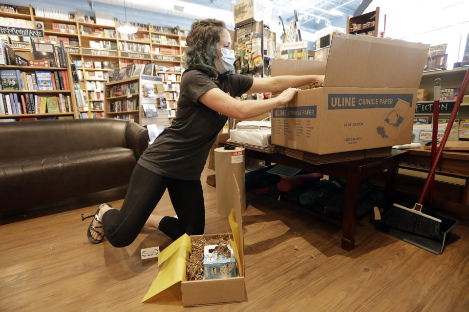 In this Thursday, June 25, 2020, photo, Cat Bock packs items for shipping to a customer from Parnassus Books in Nashville, Tenn. The retail floor of the independent bookstore has essentially become a distribution center since it is closed to customers during the coronavirus pandemic. (AP Photo/Mark Humphrey)