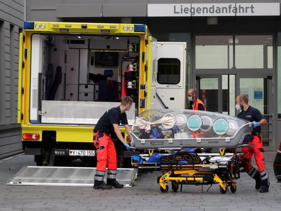 An empty stretcher is pushed by medical workers next to an ambulance outside a German hospital.