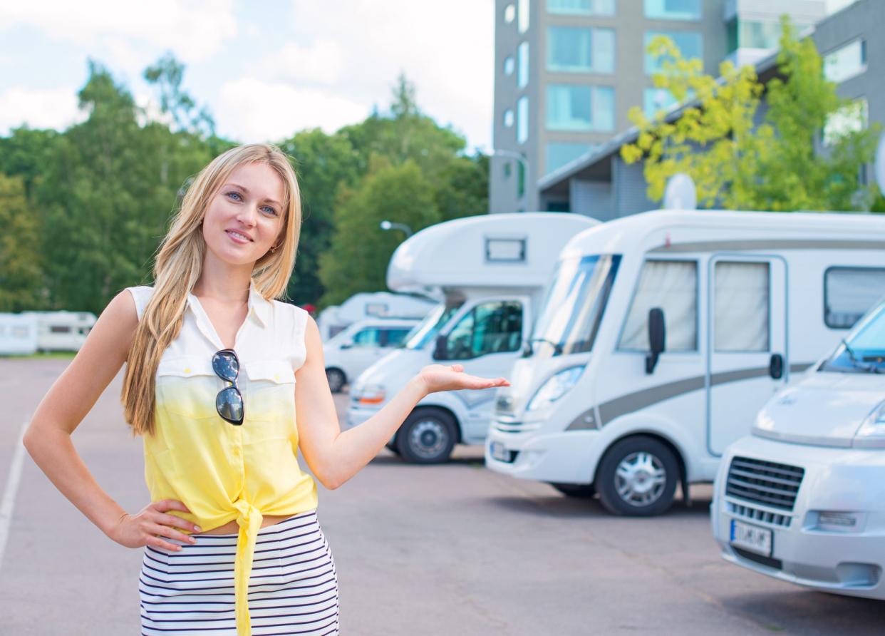 Beautiful young woman offers campervans at shop.