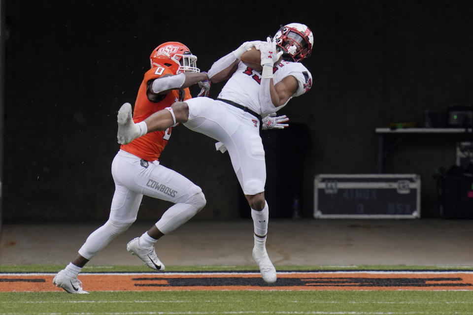 Texas Tech wide receiver Erik Ezukanma (13) catches a pass for a touchdown in front of Oklahoma State cornerback Christian Holmes (0) in the second half of an NCAA college football game in Stillwater, Okla., Saturday, Nov. 28, 2020. (AP Photo/Sue Ogrocki)