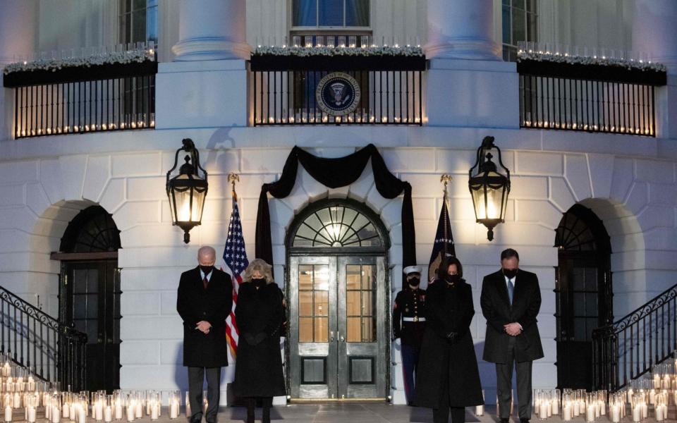 US President Joe Biden, First Lady Jill Biden, US Vice President Kamala Harris and her husband, Doug Emhoff, hold a moment of silence during a candelight ceremony in honor of those who lost their lives to coronavirus on the South Lawn of the White House  - SAUL LOEB / AFP