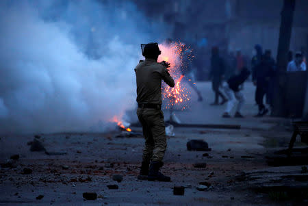 FILE PHOTO: An Indian police officer fires a tear gas shell towards demonstrators, during a protest against the recent killings in Kashmir, in Srinagar May 8, 2018. REUTERS/Danish Ismail/File Photo