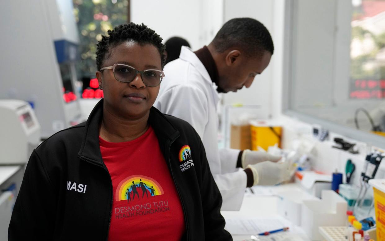 Clinical trials co-ordinator Thandeka Nkosi, poses for a photo as lab technician Xolile Mhlanga, who works with vials of the anti-HIV drug lenacapavir, works in the background at the Desmond Tutu Health Foundation's Masiphumelele Research Site, in Cape Town, South Africa