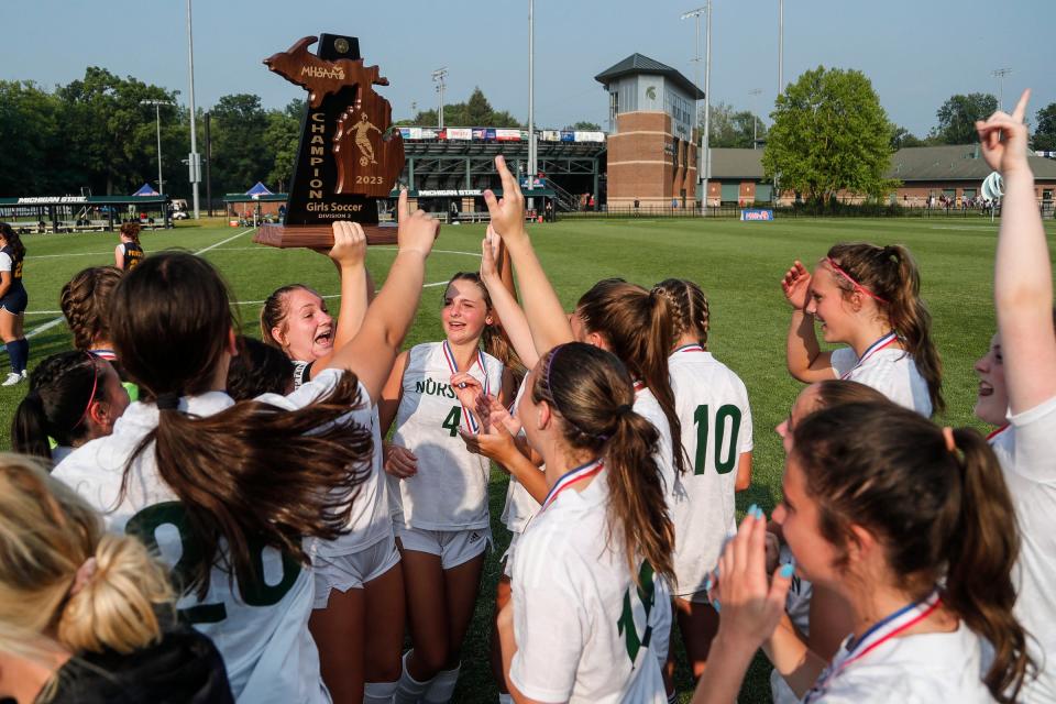 Grosse Pointe North midfielder Amelia Streberger (7) lifts up the state championship trophy to celebrate with teammates after shoot-out win over East Grand Rapids at MHSAA Division 2 girls soccer state final at DeMartin Soccer Complex in East Lansing on Friday, June 16, 2023.