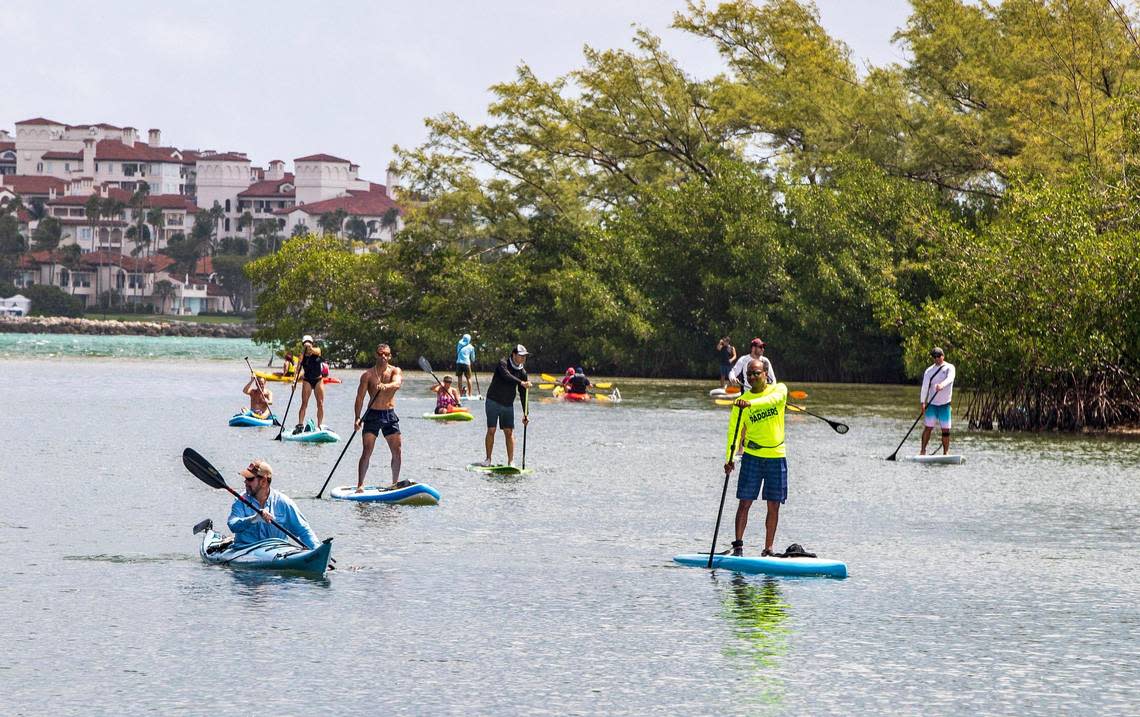 A group of outdoor enthusiasts including outgoing City of Miami Commissioner Ken Russell (center in black) took to the water on paddleboards and kayaks at the Virginia Key Outdoor Center lagoon to protest a proposal to build tiny homes on the key for homeless people.