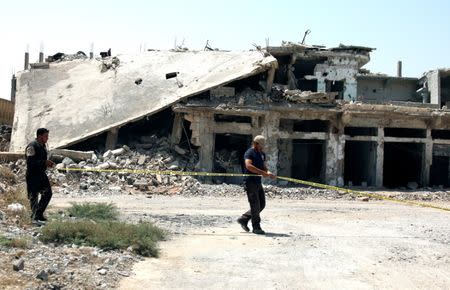 Civil defense members are seen at a damaged site in the rebel-held area in Deraa, Syria July 26, 2017. REUTERS/Alaa al-Faqir