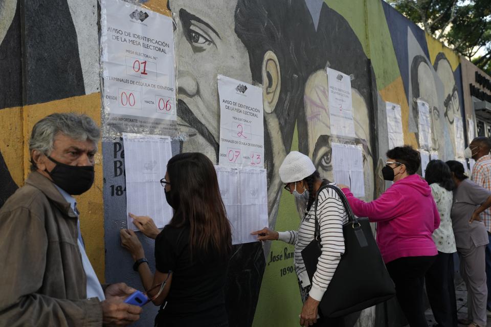 People search their ID number on a voters´ list outside of a voting center in Caracas, Sunday, Nov 21, 2021. Venezuelans go to the polls to elect state governors and other local officials. (AP Photo/Ariana Cubillos)