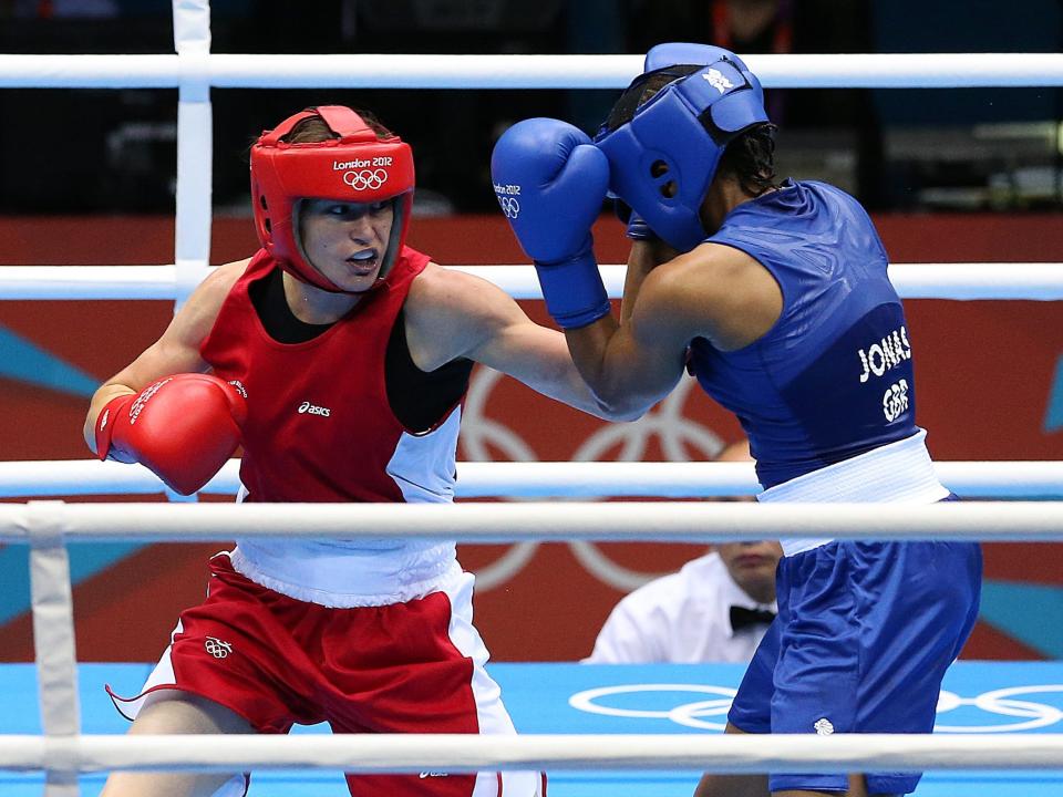 Boxers in red and blue uniforms face each other in the ring while competing in the 2012 Olympics.