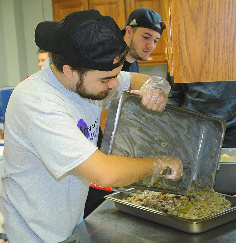 University of Mount Union student Brandon Mazzei prepares a tray of green bean casserole Sunday, Nov. 13, 2022, during the annual Community Thanksgiving Luncheon at the Alliance Salvation Army. Looking on is Alex Heighberger.