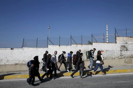 A travel agency employee (R) escorts refugees and migrants to buses heading to the borders of Greece with Macedonia, following their arrival on the Blue Star Patmos passenger ship at the port of Piraeus, near Athens, Greece, October 6, 2015. REUTERS/Alkis Konstantinidis