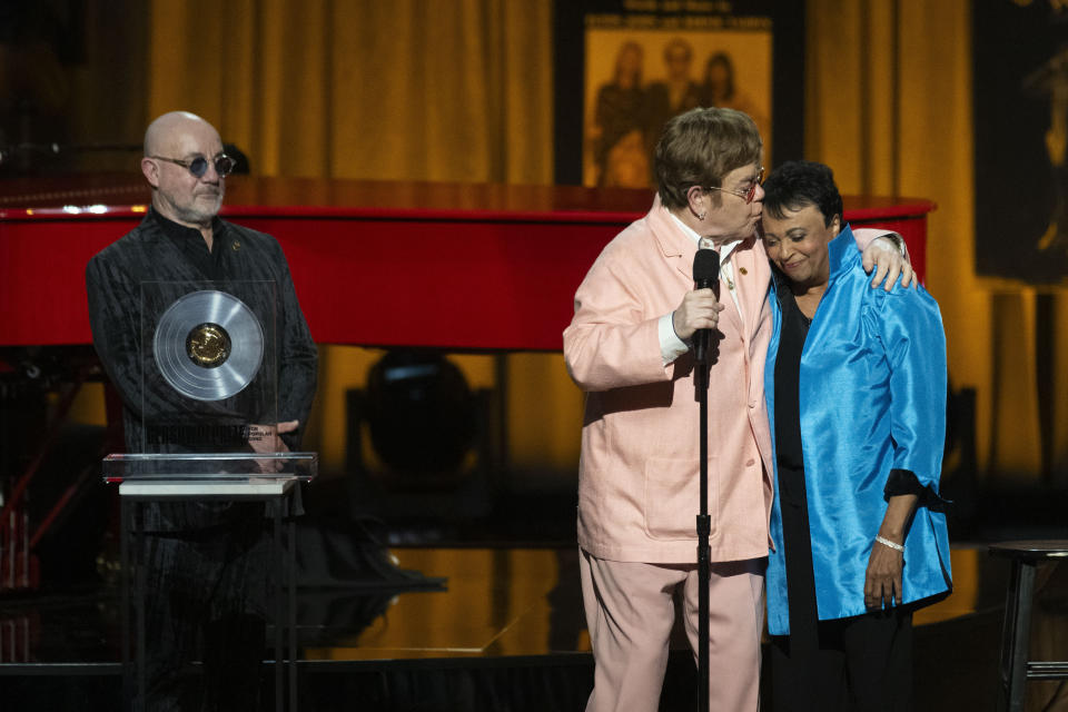 Elton John besa a la bibliotecaria del congreso Carla Hayden, derecha, después de recibir el Premio Gershwin junto con su compañero de composición Bernie Taupin, izquierda, en la ceremonia y concierto del Premio Gershwin a la Canción Popular de la Biblioteca del Congreso 2024 en el DAR Constitution Hall el miércoles 20 de marzo de 2024, en Washington. (Foto AP/Kevin Wolf)