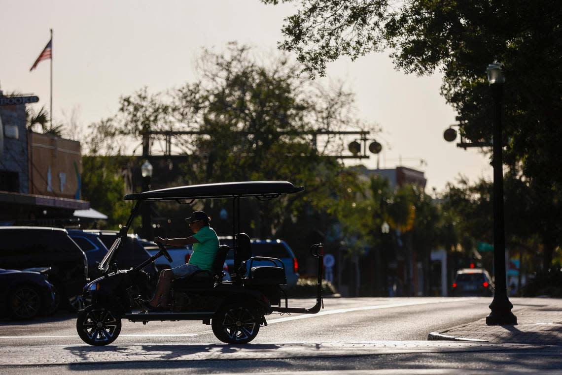 A golf cart crosses Main Street in the evening light Thursday, April 20, 2023 in Dunedin. Many residents use golf carts within the city limits.