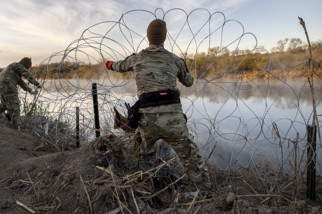  Texas National Guard troop puts up razor wire along the Rio Grande river. 