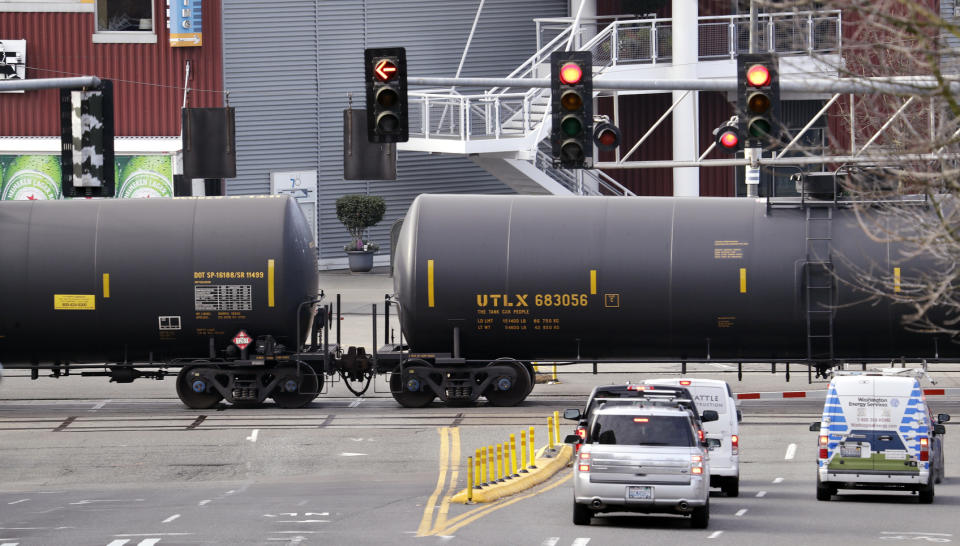 FILE - In this Feb. 13, 2018, file photo, automobile traffic waits at a train crossing as train cars that carry oil are pulled through downtown Seattle. Attorneys general for North Dakota and Montana have petitioned the Trump administration Wednesday, July 17, 2019, to overrule a Washington state law that imposes safety restrictions on oil shipped by rail from the Northern Plains. (AP Photo/Elaine Thompson, File)