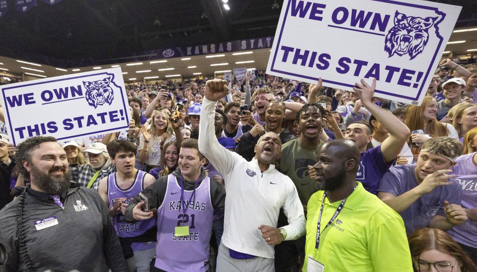 Kansas State coach Jerome Tang, middle, celebrates with fans after his team knocked of rival Kansas.