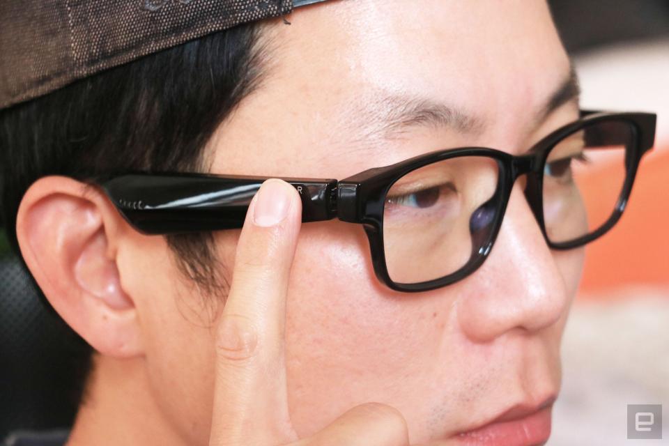 <p>Razer Anzu smart glasses review photo. Right side profile of a man wearing the Razer Anzu smart glasses with his right index finger up to the touch-sensitive arm.</p>
