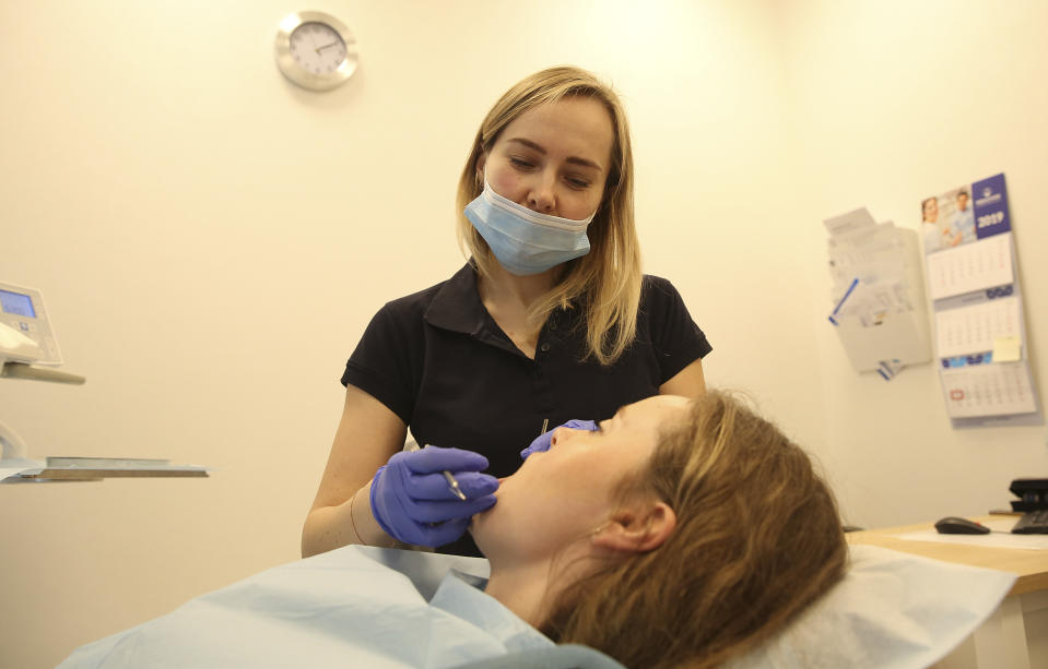 Olena Aleksiychuk, a Ukrainian dentist, treats a patient, who is also Ukrainian, at a private dental clinic in Warsaw, Poland, on Monday March 11, 2019. 31-year old Ukrainian dentist Aleksiychuk, left behind her parents, a home and her private dental practice in Ukraine four years ago, to learn how to speak Polish and seek the opportunity of working abroad. (AP Photo/Czarek Sokolowski)