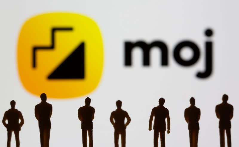 Small toy figures are seen in front of displayed Moj logo in this illustration taken