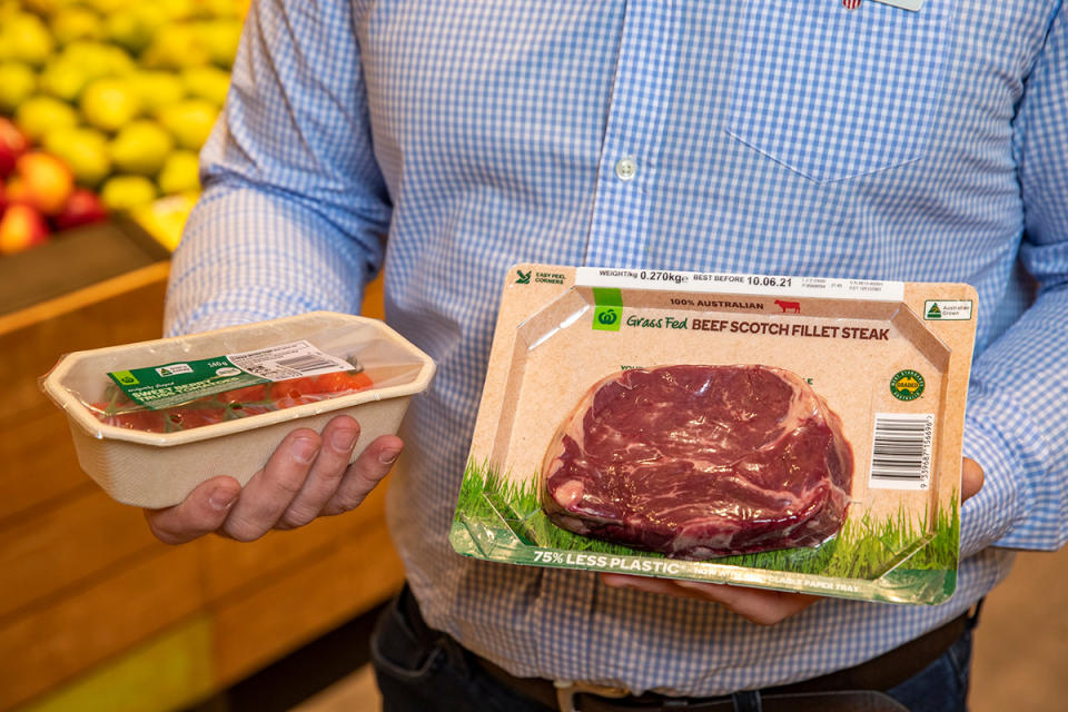 Woolworths worker holds tomato and meat tray.