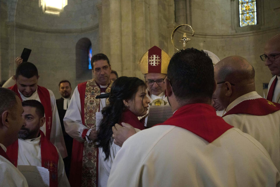 Sally Ibrahim Azar, center, a Palestinian Christian and Council member of the Lutheran World Federation is applauded by clergy after she was ordained as the first female pastor in the Holy Land, in the Old City of Jerusalem, Sunday, Jan. 22, 2023. (AP Photo/ Maya Alleruzzo)