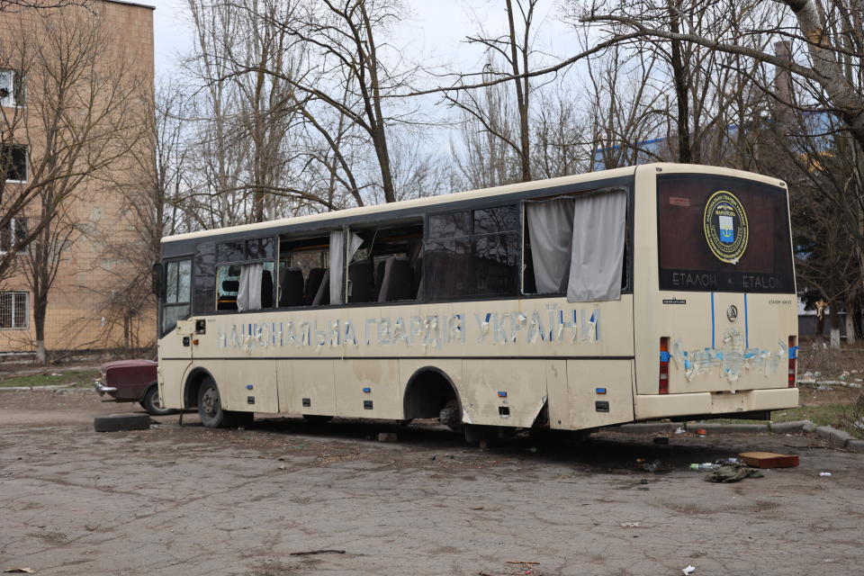 A military bus without one set of wheels and its previous designation painted out. 