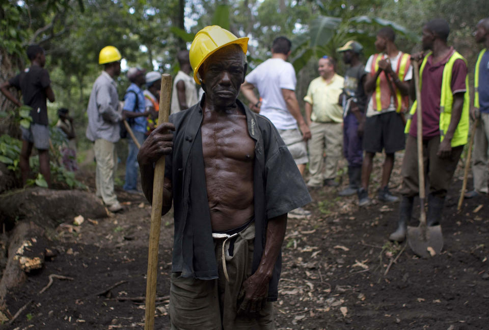 In this April 10, 2012 photo, Genove Valcimon, 70, poses for a picture as he works on a road being built through the mountains to lead to an exploratory drill site in the department of Trou Du Nord, Haiti. Haiti's land may yet hold the solution to centuries of poverty: there is gold hidden in its hills, and silver and copper too. Now, two mining companies are drilling around the clock to determine how to get those metals out, and how much it might cost.  (AP Photo/Dieu Nalio Chery)