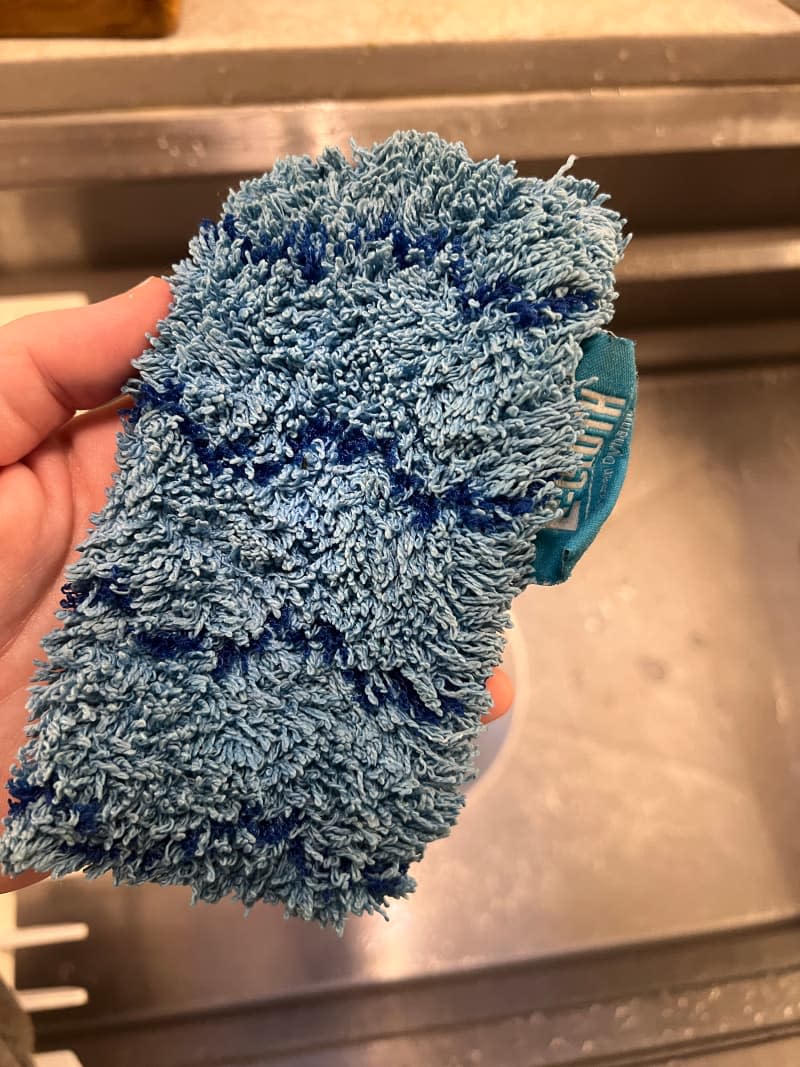 Someone holding sponge above the sink.