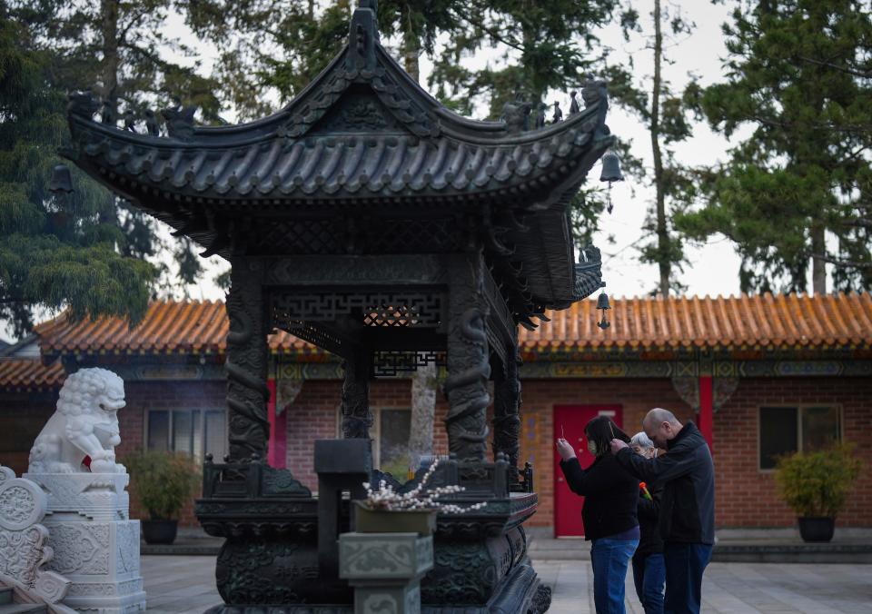 People hold burning incense sticks while pausing to mark the Lunar New Year at the International Buddhist Temple at dusk in Richmond, British Columbia, Friday, Feb. 9, 2024.