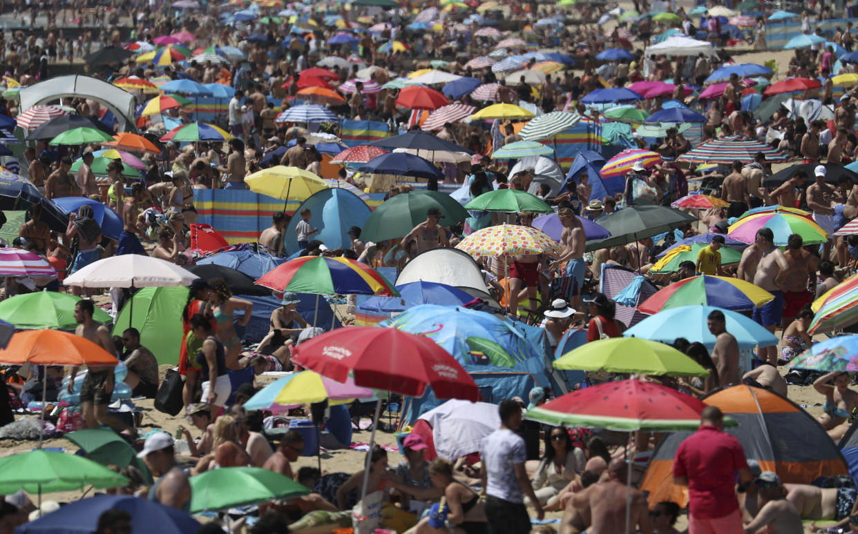 Crowds gather on the beach in Bournemouth, England, Thursday June 25, 2020, as coronavirus lockdown restrictions have been relaxed. According to weather forecasters Thursday could be the UK's hottest day of the year, so far, with scorching temperatures forecast to rise even further. (Andrew Matthews/PA via AP)