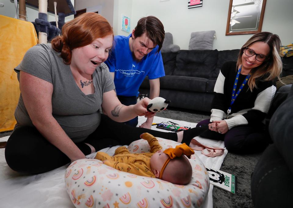 Mariah Denis, left, shows a toy to her newborn daughter Maelynn Spencer, 1 month, with dad Cody Spencer, center, and the home visitor Erin Rosinsky-Gauthier, Thursday, April 4, 2024, in Two Rivers, Wis.