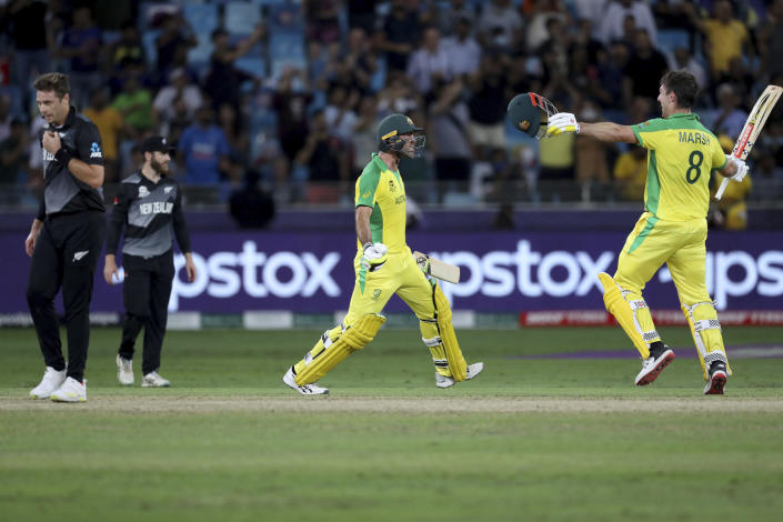 Australia's Glenn Maxwell, second right, celebrates hitting a four to win the tournament, with his teammate Mitchell Marsh, right, as New Zealand's captain Kane Williamson, second left, and Tim Southee, left, react, during the Cricket Twenty20 World Cup final match between Australia and New Zealand in Dubai, UAE, Sunday, Nov. 14, 2021. Australia won by 8 wickets. (AP Photo/Kamran Jebreili)