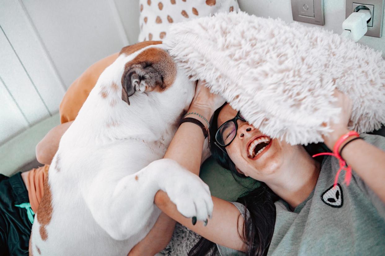 woman belly laughing and loving her dog kisses