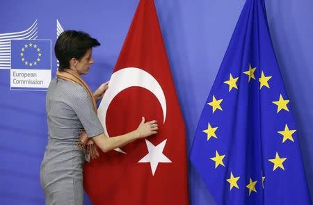 A woman adjusts the Turkish flag next to the European Union flag before the arrival of Turkish Prime Minister Ahmet Davutoglu (unseen) at the EU Commission headquarters in Brussels January 15, 2015. REUTERS/Francois Lenoir