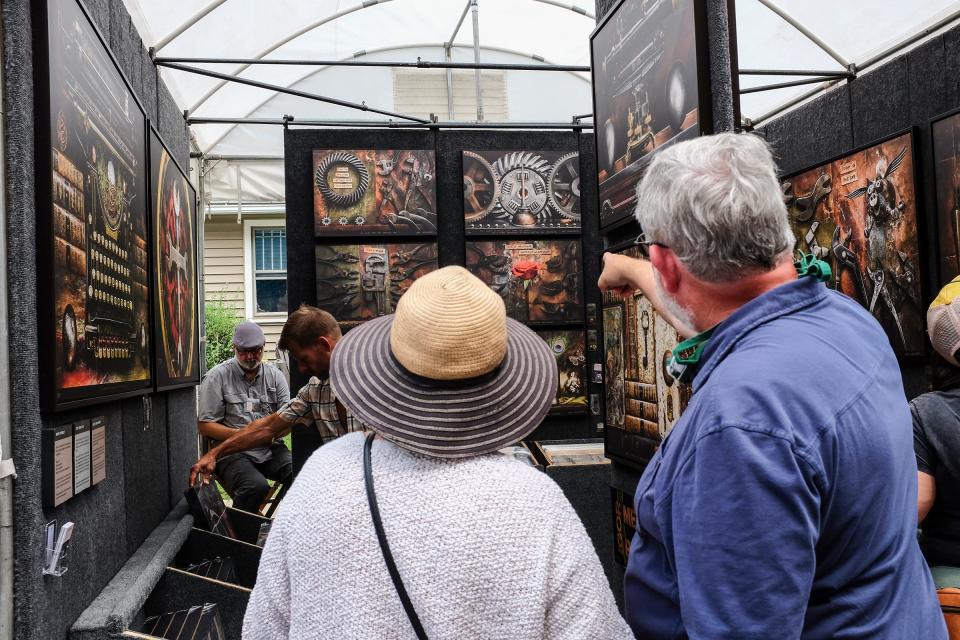 People check out the artwork at the East Lansing Art Festival Sunday, Aug. 8, 2021.