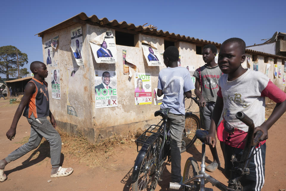 Children outside a public toilet plastered with campaign posters on the outskirts of Harare, Wednesday Aug. 16, 2023. Zimbabwe's main opposition leader Nelson Chamisa is surrounded by security as he leaves his last campaign rally in Harare, Monday, Aug 21, 2023. The upcoming general election in Zimbabwe is crucial to determining the future of a southern African nation endowed with vast mineral resources and rich agricultural land. But for many in the educated but underemployed population, the daily grind to put food on the table inhibits interest in politics. (AP Photo/Tsvangirayi Mukwazhi)