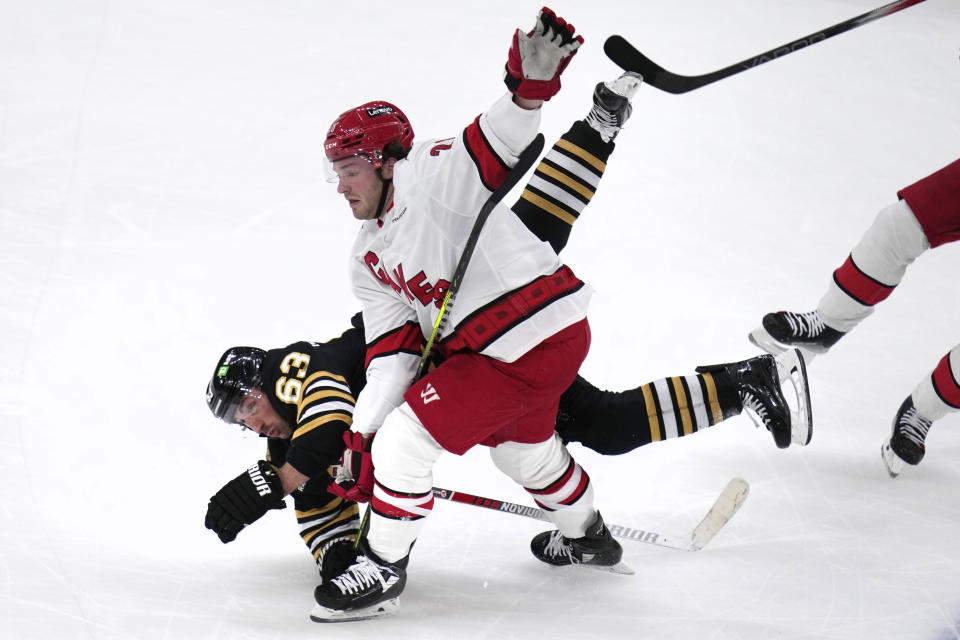 Boston Bruins left wing Brad Marchand (63) falls after being tripped by Carolina Hurricanes left wing Brendan Lemieux (28) during the second period of an NHL hockey game Wednesday, Jan. 24, 2024, in Boston. (AP Photo/Charles Krupa)