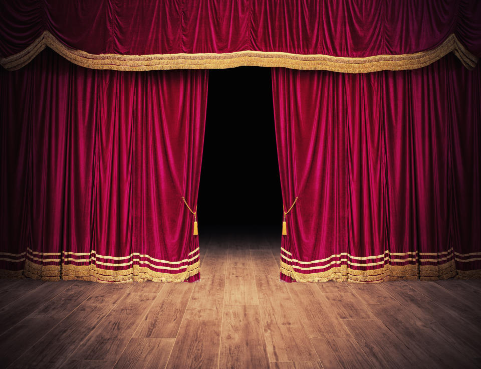 The red curtains of the stage are opening for the theater show