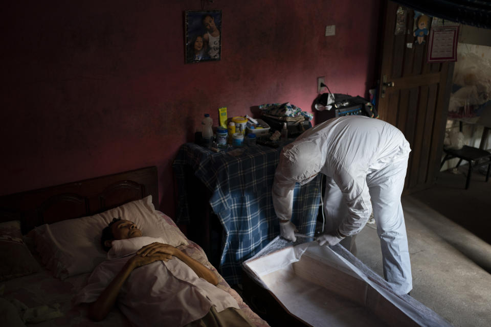 A SOS Funeral worker wearing protection equipment amid the new coronavirus pandemic prepares to remove the body of Eldon Cascais in Manaus, Brazil, Saturday, May 9, 2020. According to relatives, Cascais had lung cancer and died at home after suffering from shortness of breath, cough and fatigue for a week. (AP Photo/Felipe Dana)