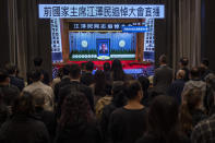 Residents watch a live broadcast of the memorial service for late former Chinese President Jiang Zemin on a screen at a community center in Hong Kong, Tuesday, Dec. 6, 2022. A formal memorial service was held Tuesday at the Great Hall of the People, the seat of the ceremonial legislature in the center of Beijing. Words on screen read "Former Chairman Jiang Zemin memorial live broadcast." (AP Photo/Vernon Yuen)