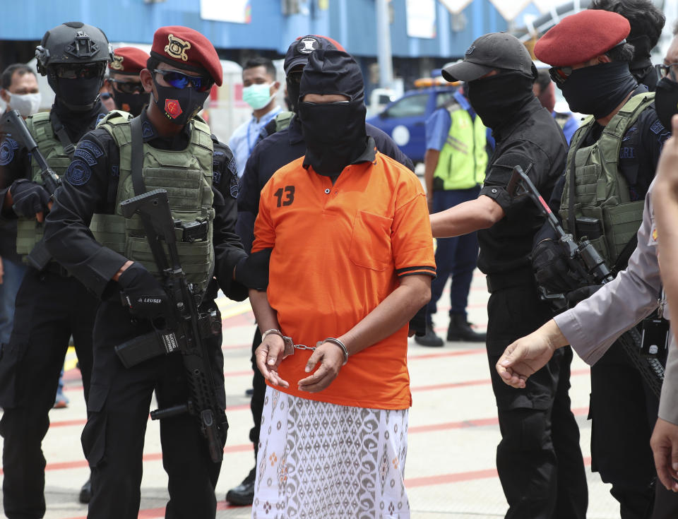 Police officers escort suspected militant Zulkarnaen, center, who is also known as Aris Sumarsono, upon arrival at Soekarno-Hatta International Airport in Tangerang, Indonesia, Wednesday, Dec. 16, 2020. Indonesian authorities have transferred suspected militants arrested in recent weeks to the country’s capital, including Zulkarnaen, a bomb maker and the architect of a series of deadly attacks and sectarian conflicts in the world’s largest Muslim majority nation.(AP Photo/Achmad Ibrahim)