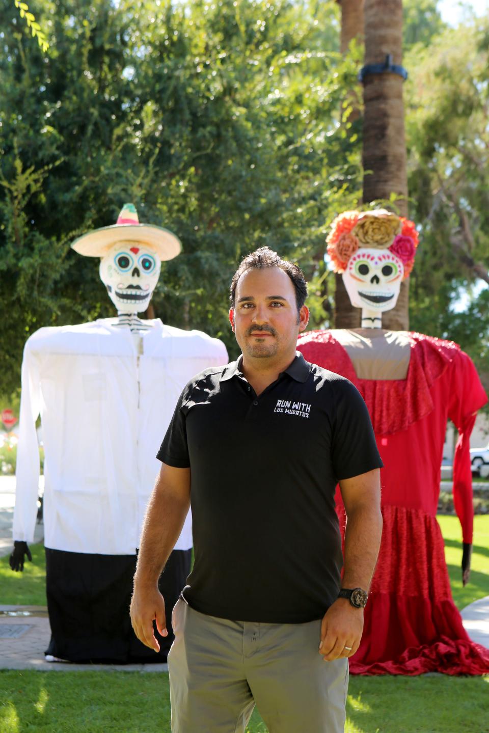 Run With Los Muertos 5K race director, Tizoc DeAztlan, stands next to puppets for the processional prior to the start of the 2019 race.